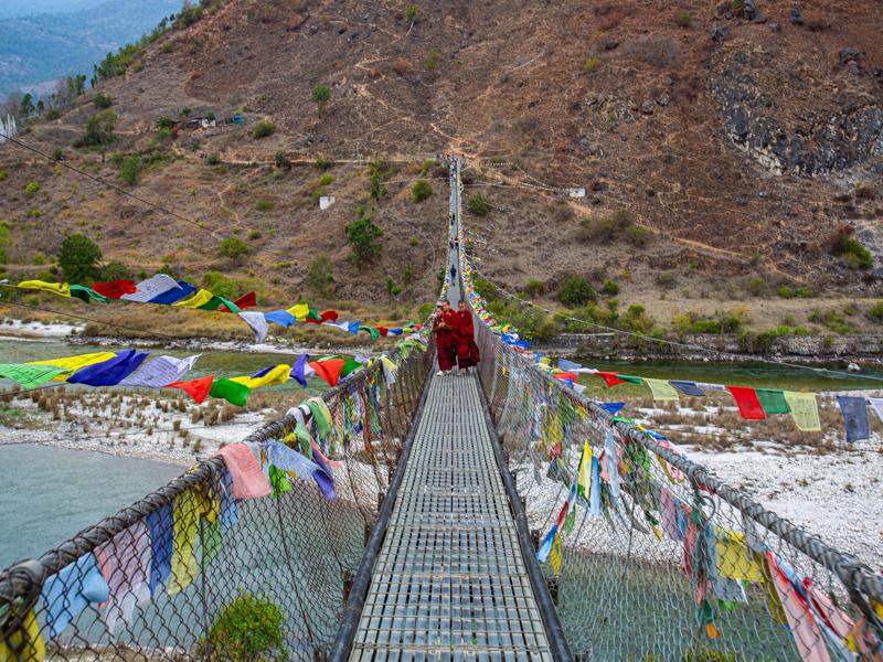 Monks on the footbridge over river