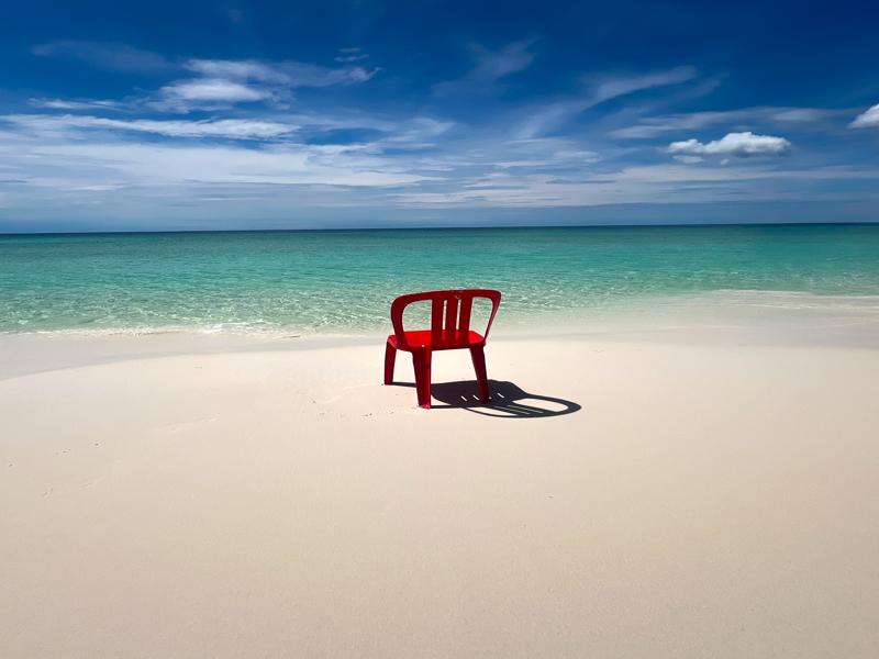 A lonely red chair washed up on the beach
